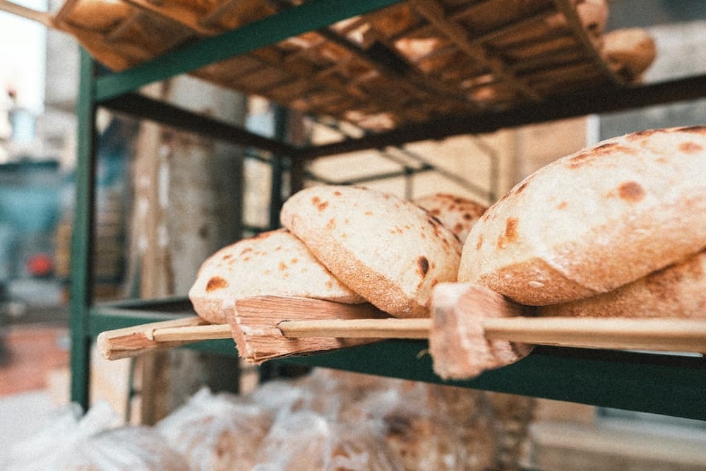 Freshly baked traditional Egyptian aish baladi bread on a wooden rack.