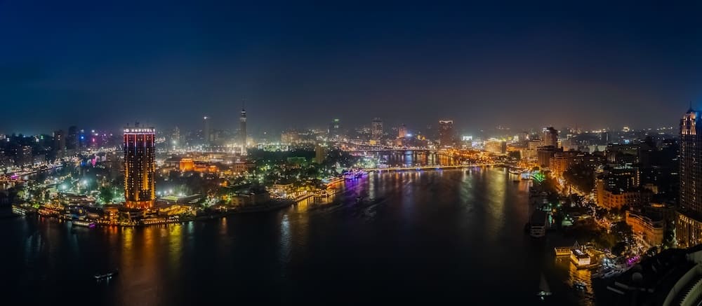 Panoramic view of Cairo illuminated at night along the Nile River.