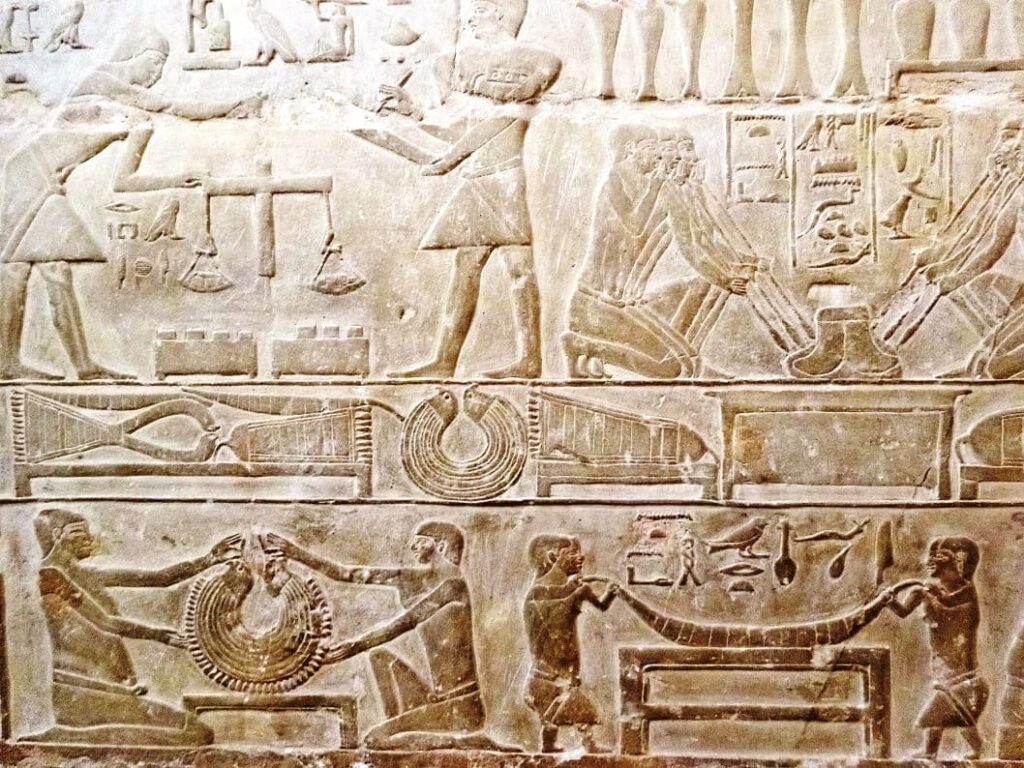 Detailed Egyptian bas-relief carving depicting various scenes of daily life and symbolic elements, such as offerings and sacred animals