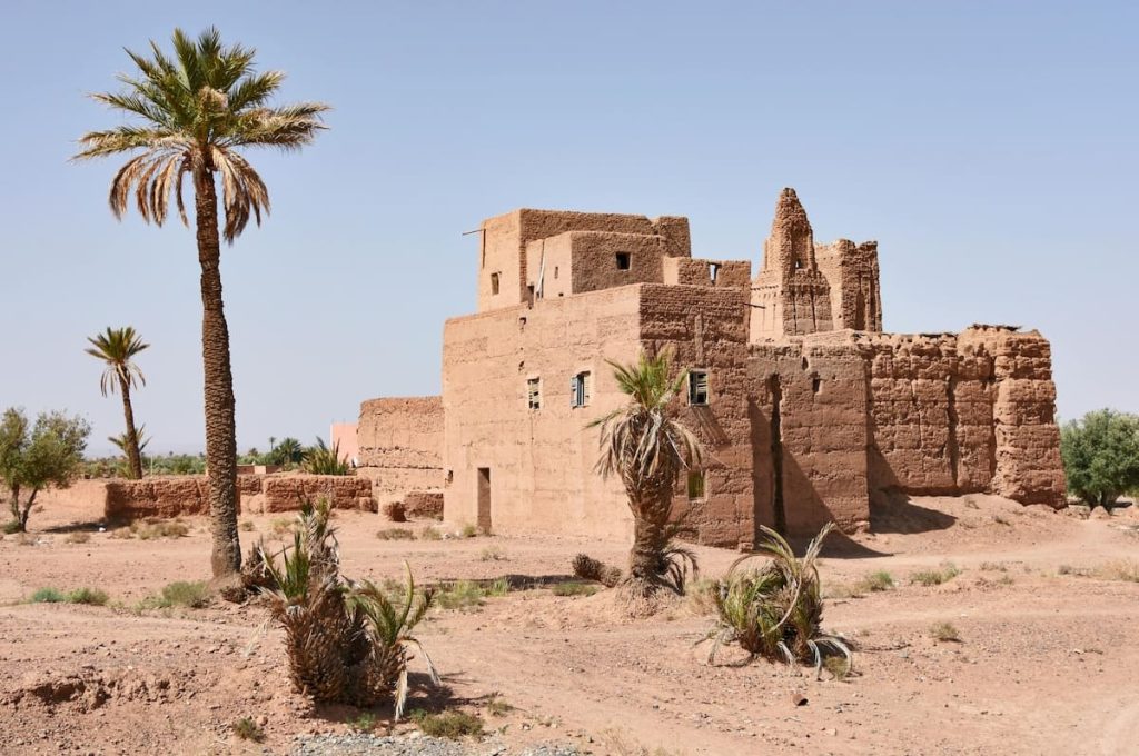 Ancient mud-brick ruins stand amidst palm trees in the desert at Kharga Oasis