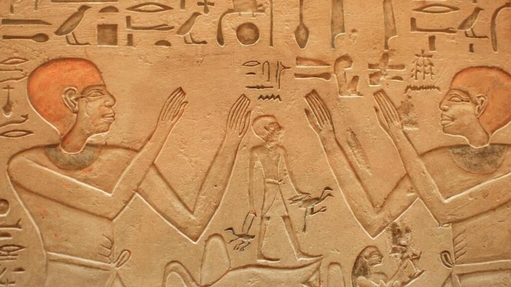 Detailed Egyptian hieroglyphic carvings on a wall depicting figures in traditional poses.