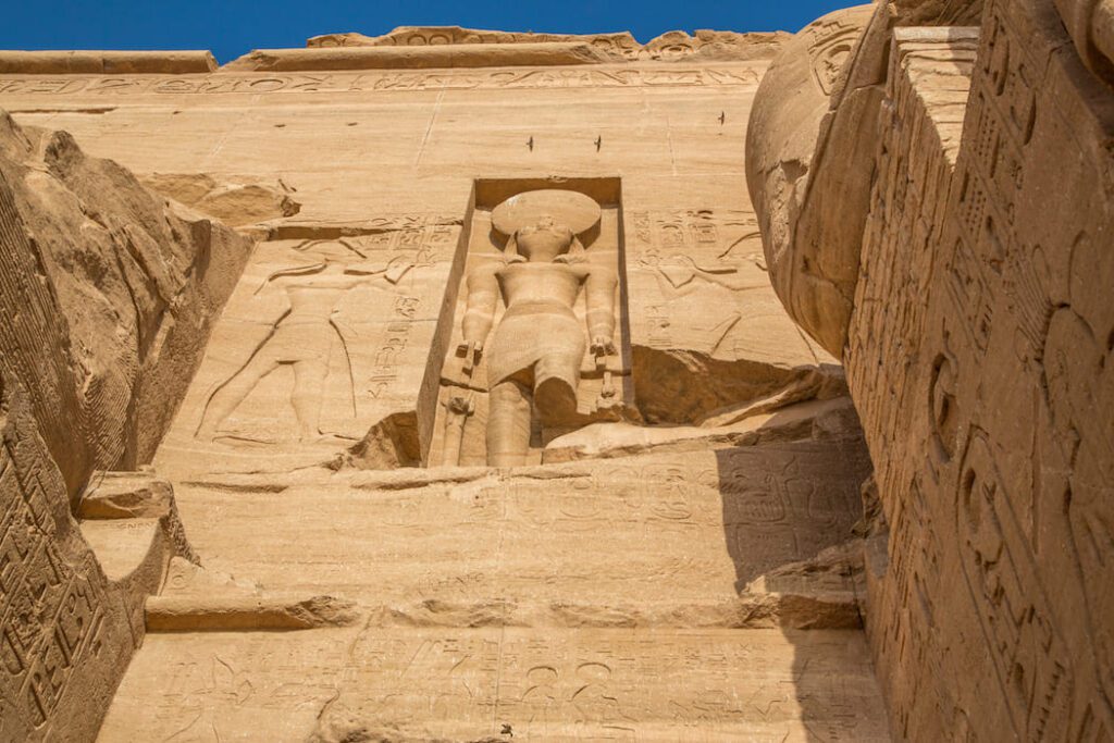 A recessed statue of Ramses II framed by hieroglyph-covered walls at Abu Simbel.