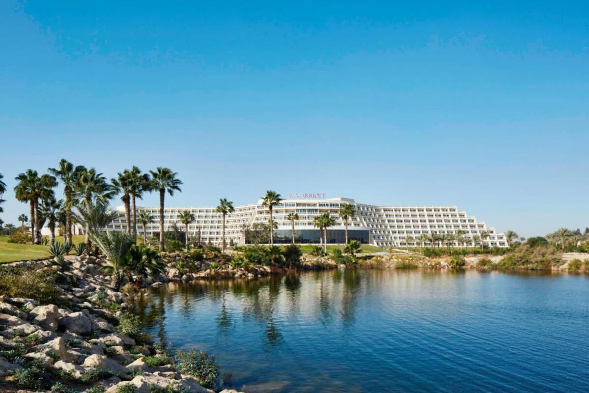 Exterior view of JW Marriott Cairo Hotel with palm trees and blue sky