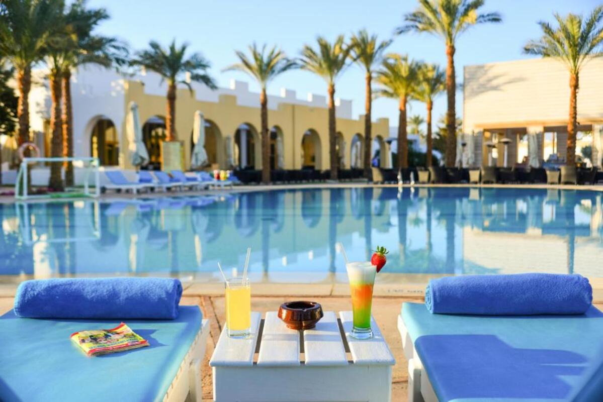 Beachfront view of Novotel Sharm El Sheikh Hotel with palm trees and sun loungers