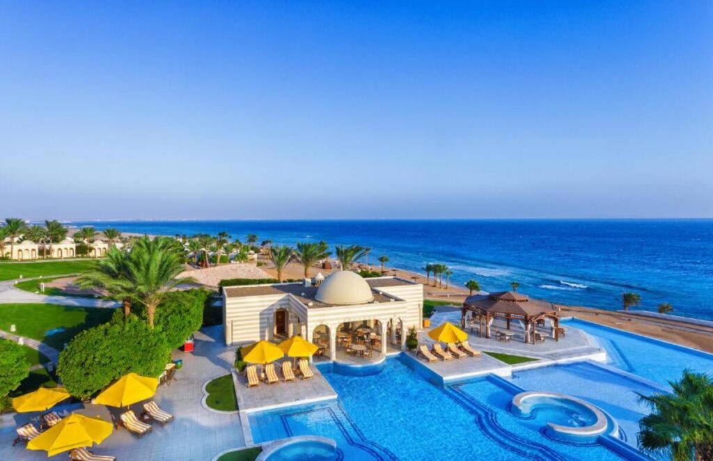 Luxurious beachfront view of The Oberoi Beach Resort, Sahl Hasheesh with clear turquoise waters and a golden sandy beach under a bright blue sky.
