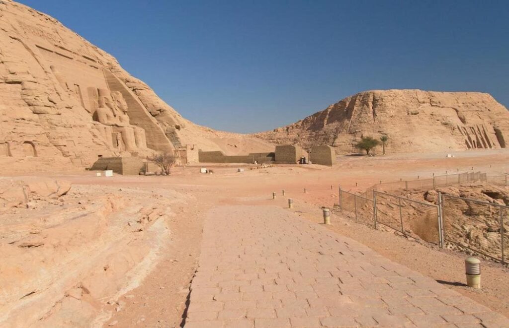 A paved path leading to the distant Abu Simbel temple in a desert landscape