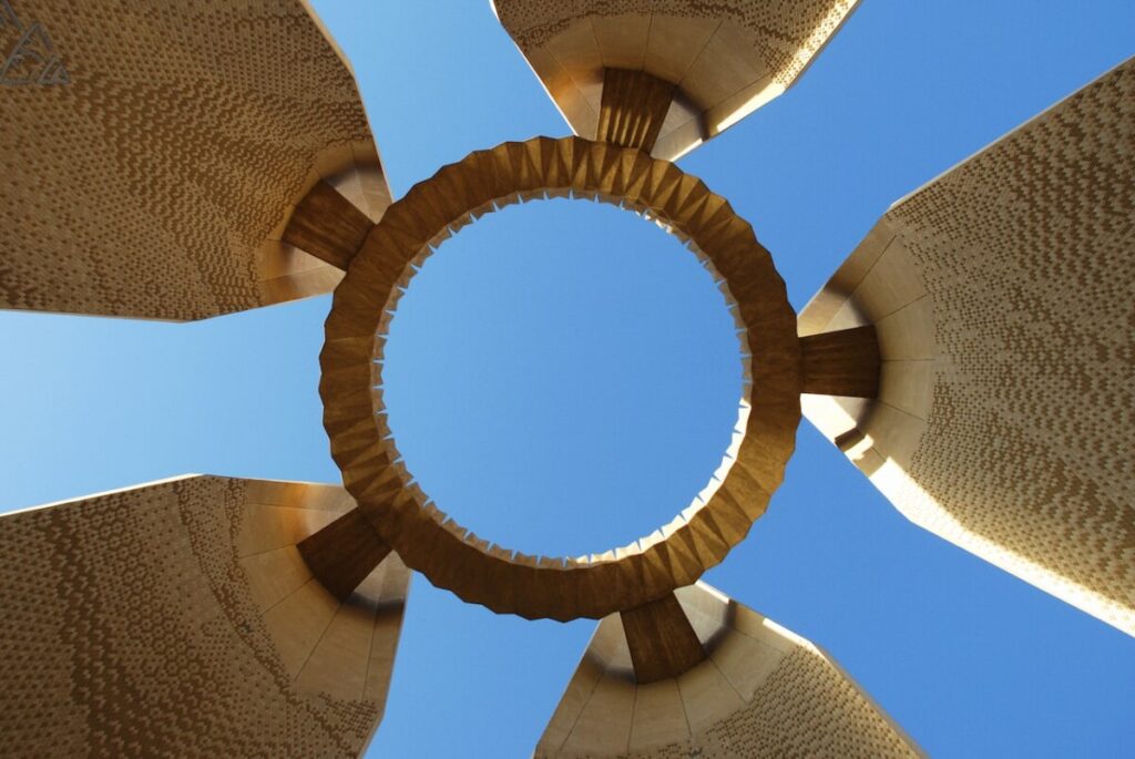 Upward view of the Aswan High Dam monument against a clear blue sky.