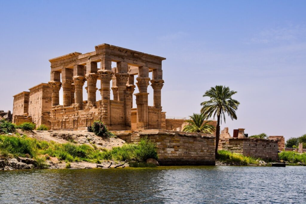 The iconic columns of the Temple of Philae against the backdrop of the Nile River.