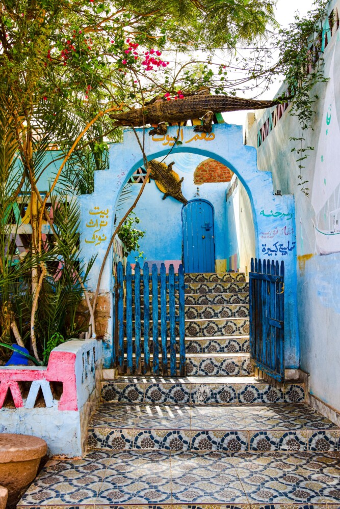 A traditional Nubian courtyard with colorful walls, mosaic tiles, and lush plants.