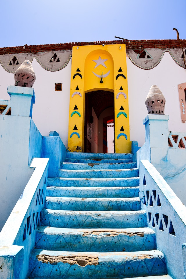 A bright yellow doorway with Nubian motifs leading into a traditional house.