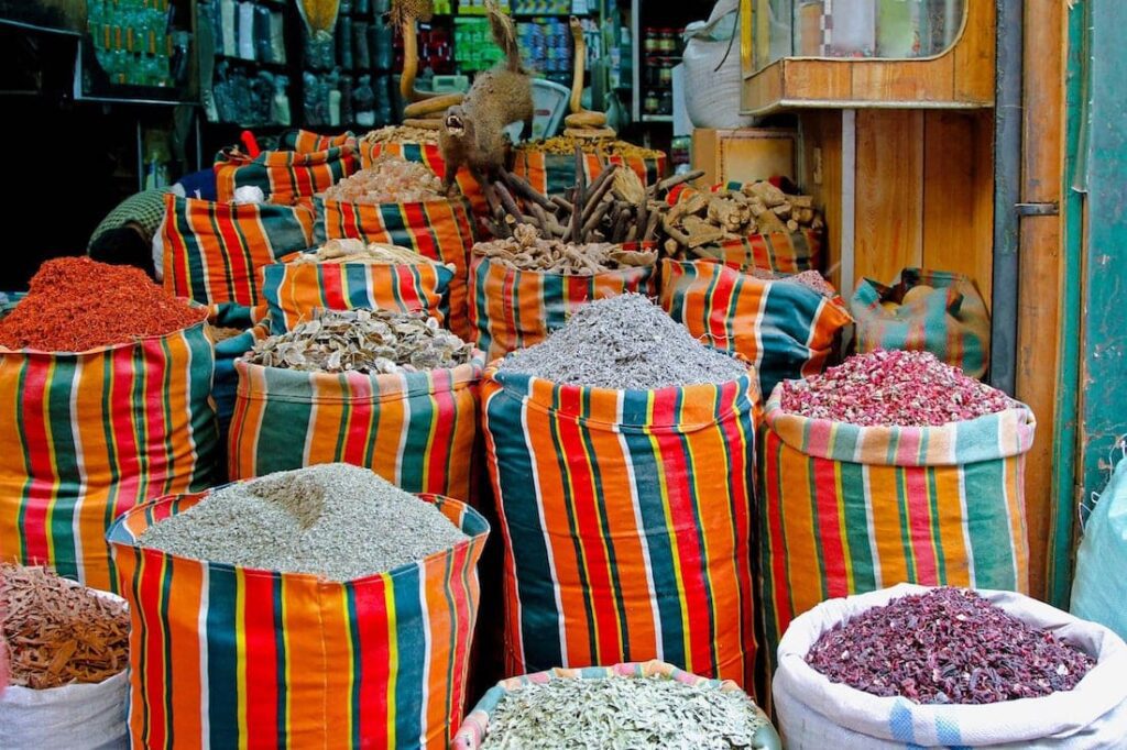Heaps of vibrant spices and herbs displayed in striped sacks at a local market.