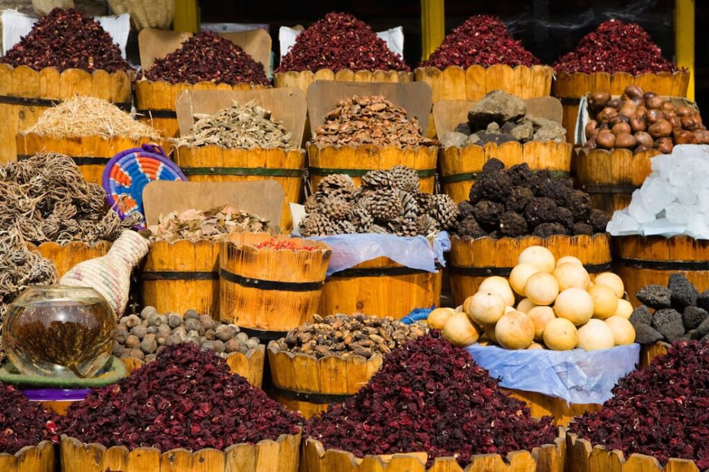 A variety of spices, herbs, and botanicals neatly arranged in wooden crates at a market stall.