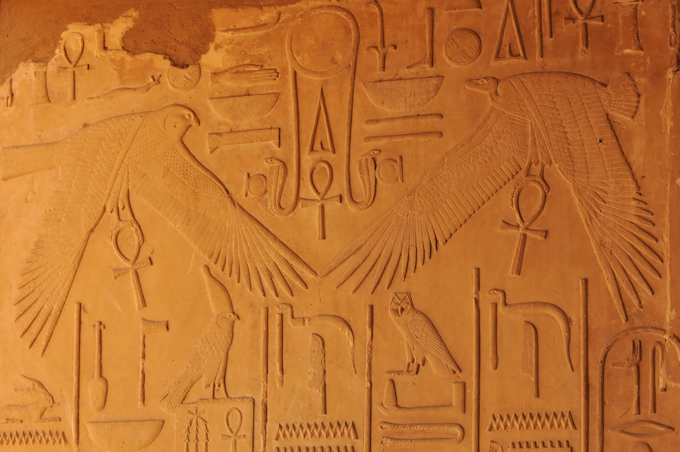 Close-up of ancient reliefs depicting gods and hieroglyphs in Isis Temple.