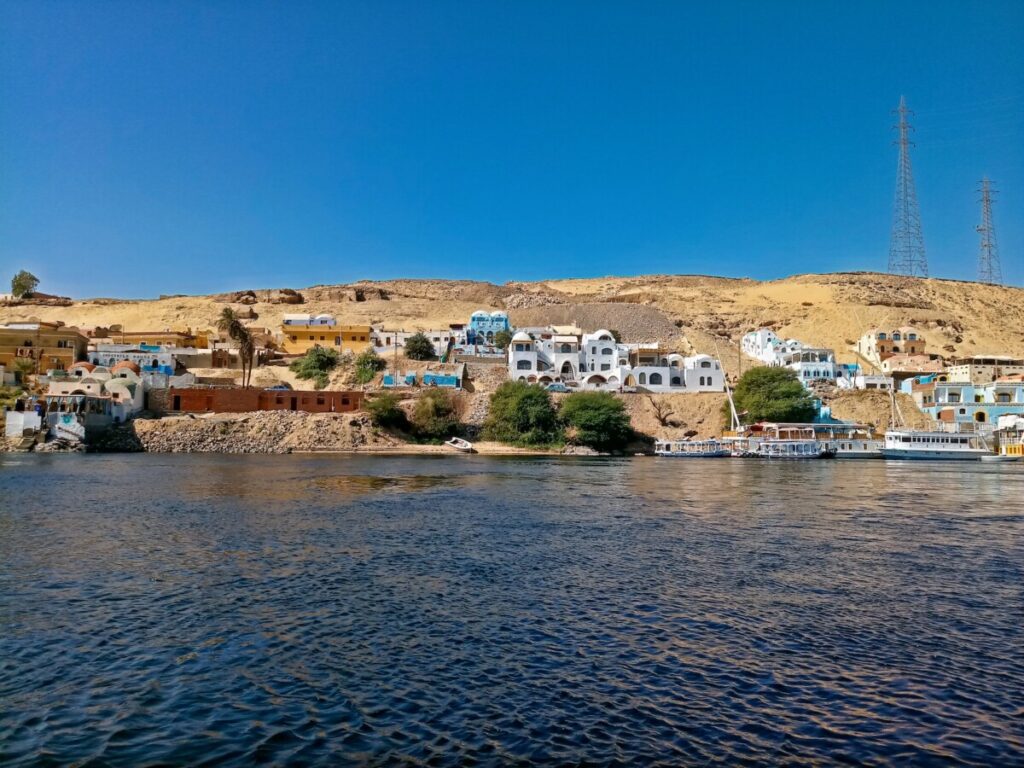 Colorful Nubian houses dot the shoreline of the Nile against a desert backdrop.