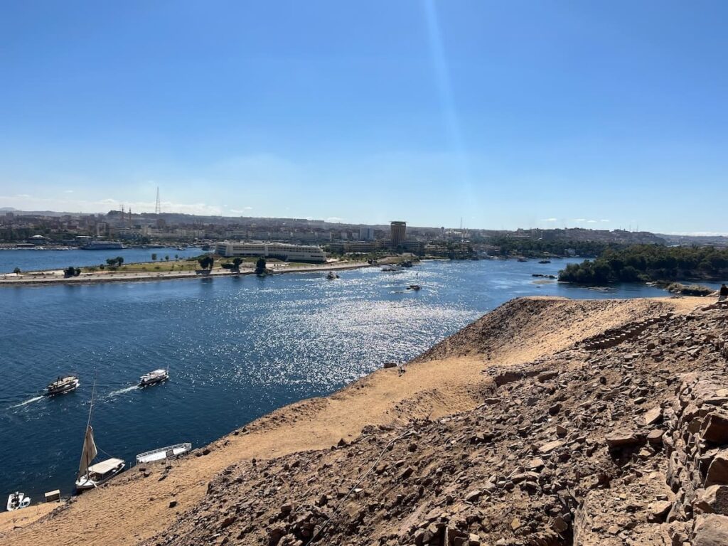 Panoramic view of the Nile River surrounded by desert and cityscape under a clear blue sky.