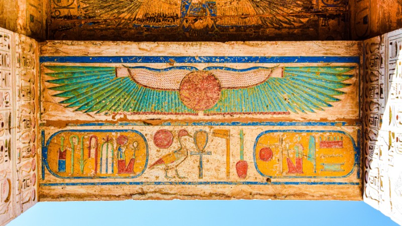 - "Vibrant ancient Egyptian hieroglyphs with a winged sun disk."