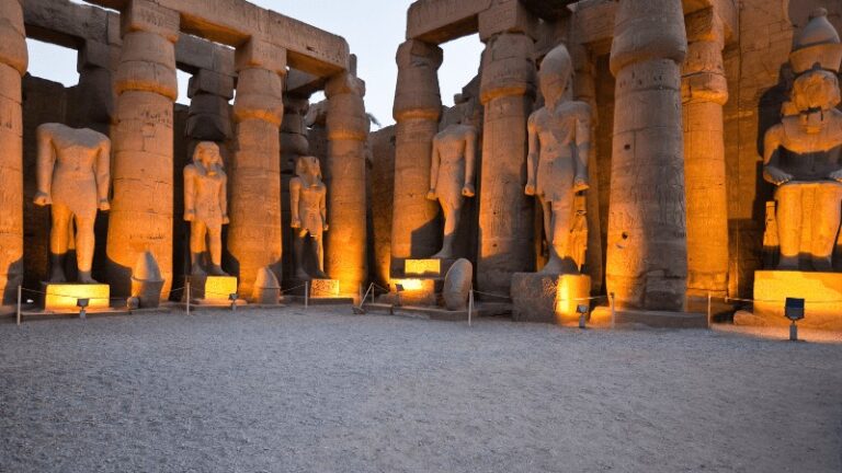 "Illuminated colossal statues in Luxor Temple at dusk."