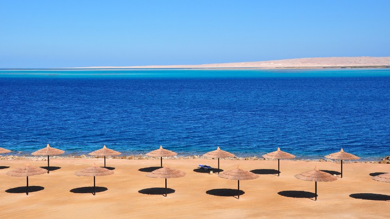 "Deserted beach with umbrellas overlooking clear blue waters."