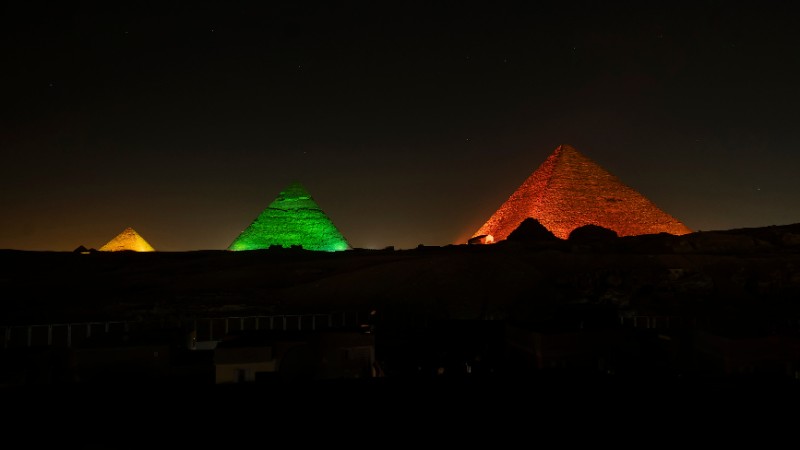 "The Pyramids of Giza lit in colorful lights at night."