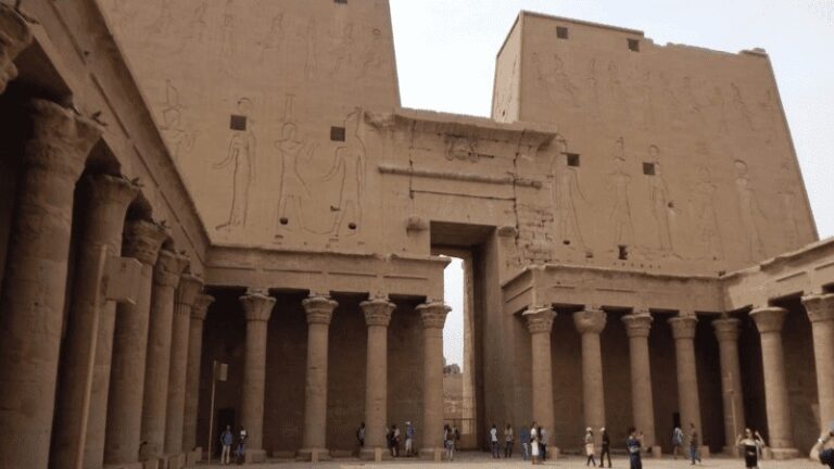 "Visitors at the entrance of Edfu Temple with hieroglyphics."