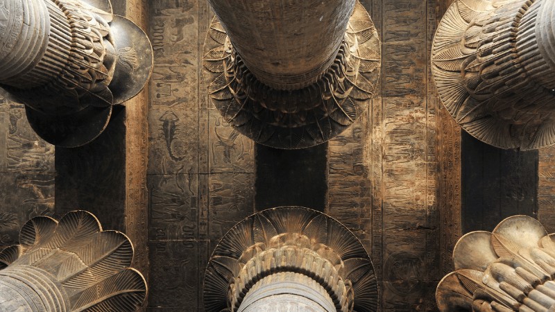 "Close-up view of ancient Egyptian temple pillars with intricate carvings and hieroglyphs."