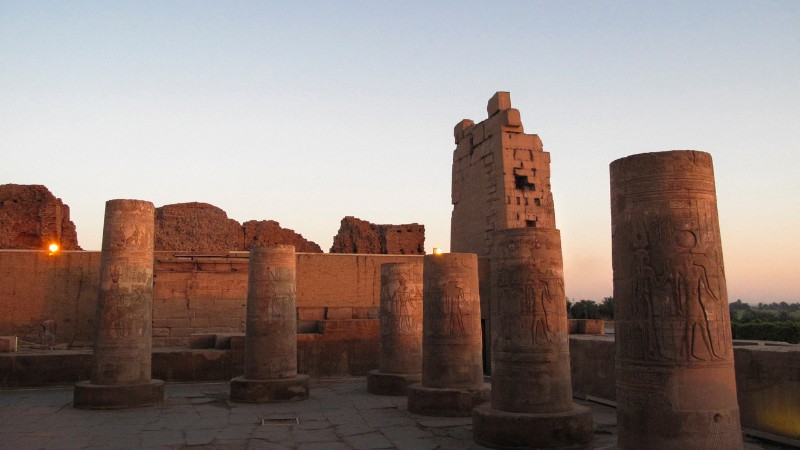 "Historic temple ruins with standing columns during sunset."