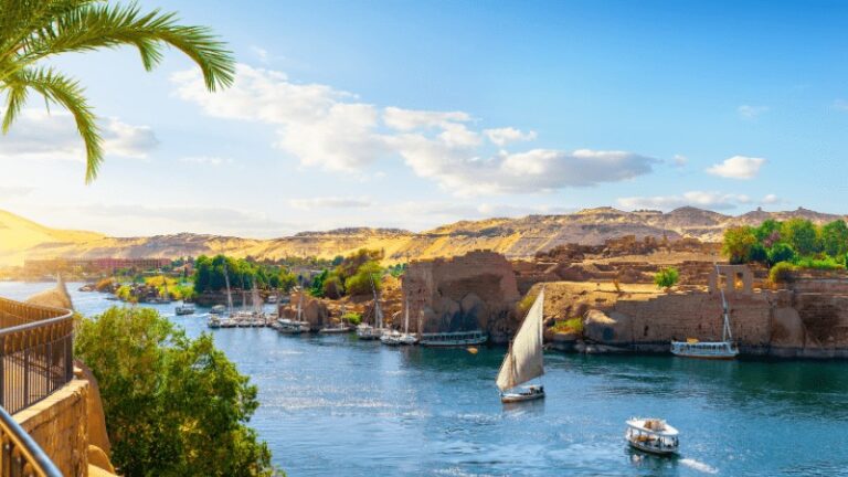 "Scenic view of the Nile river with traditional boats and rocky hills."