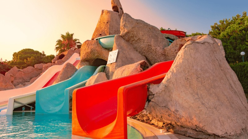 Colorful water slides at an aqua park with a sunset in the background