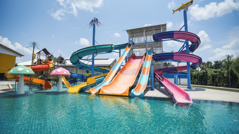 A colorful water park with multiple slides and a pool on a sunny day.