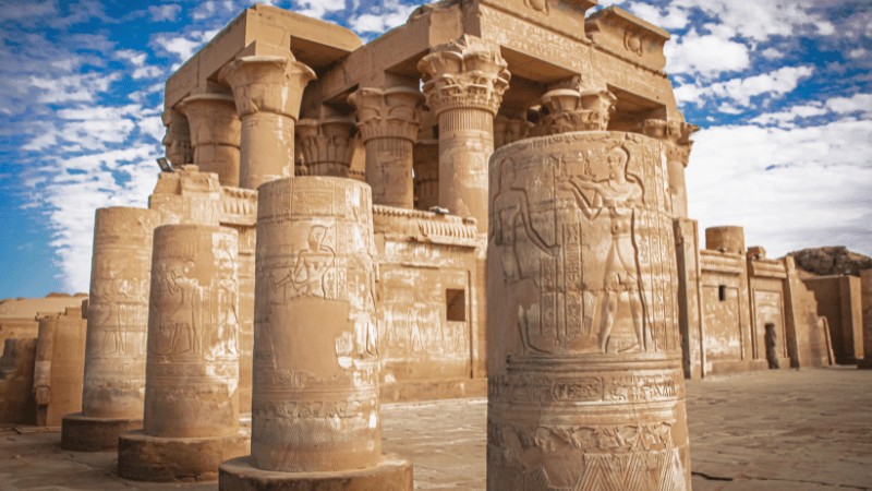 "Carved columns and hieroglyphs at the historic Kom Ombo Temple under a clear blue sky."