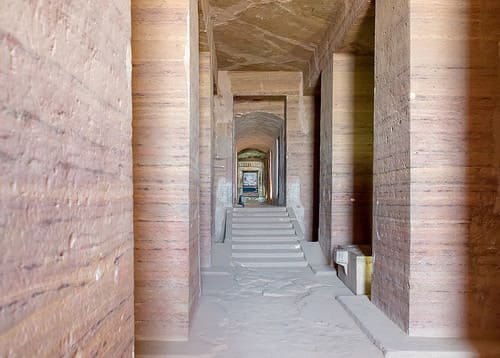 A long corridor lined with columns inside an ancient Egyptian structure.