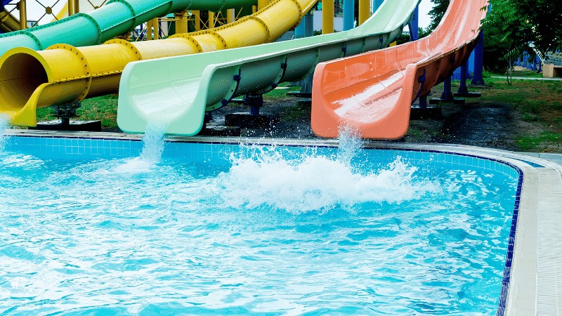 Colorful water slides ending in a pool with a splash of water.