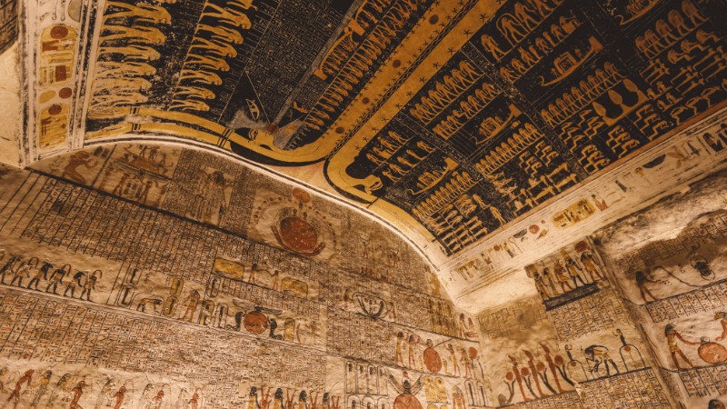 "Vivid ancient Egyptian hieroglyphs covering the walls and ceiling of a historical tomb."