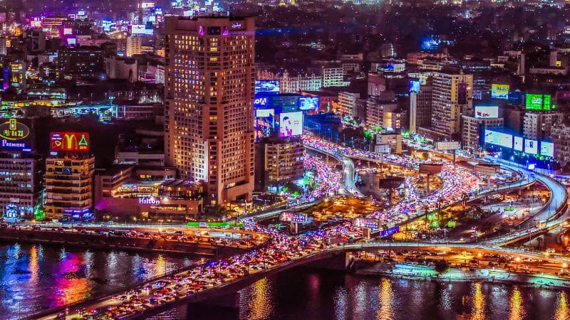 Vibrant night view of Cairo with illuminated streets and the Nile River.
