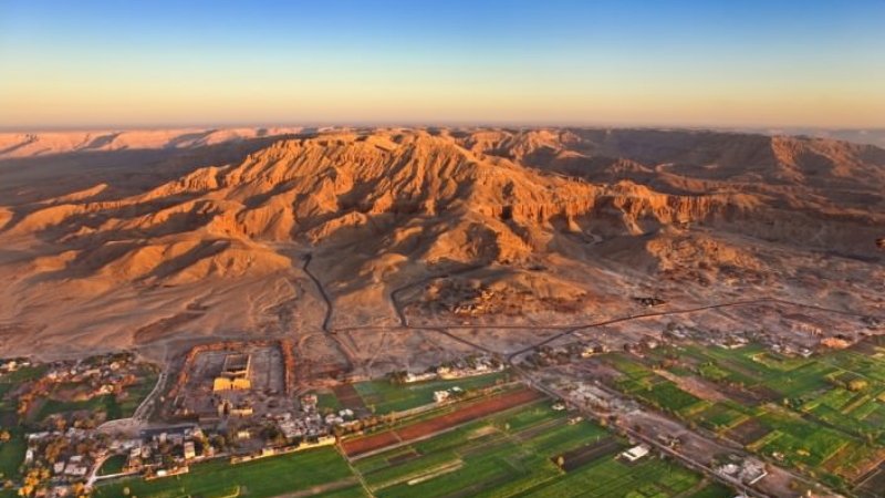 An aerial view of the lush Nile Valley against the stark backdrop of the desert mountains