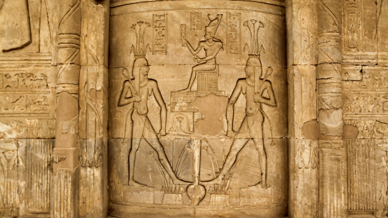 Carved hieroglyphs and figures on an ancient Egyptian temple wall.