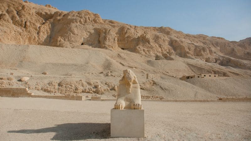 Limestone statue of a seated sphinx in the Egyptian desert with mountains in the background