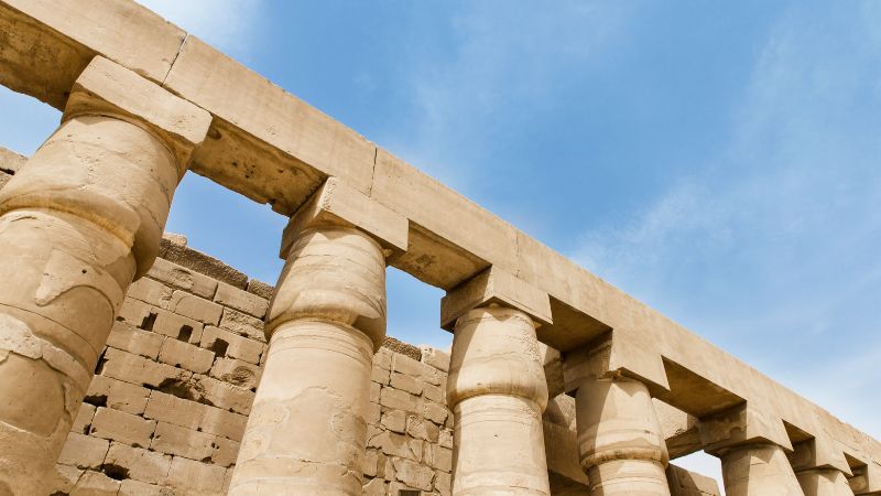 Row of large, sturdy columns under a clear sky at an ancient Egyptian temple