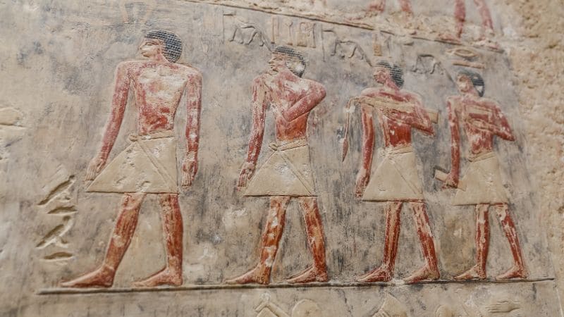 Ancient Egyptian bas-relief figures painted on tomb wall."