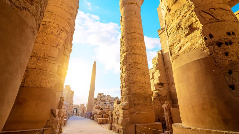 "Sunlit path between towering columns at Karnak Temple."