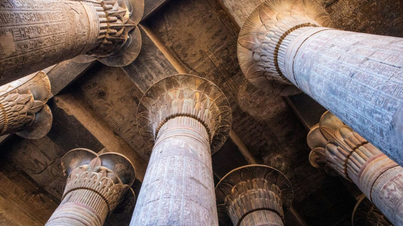 Looking up at the towering columns of an Egyptian temple, adorned with hieroglyphs