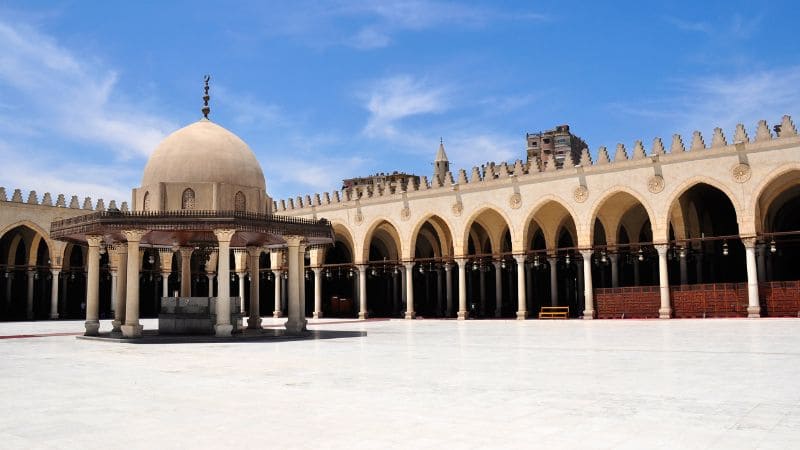 The courtyard of the Mosque of Ibn Tulun under a clear blue sky.