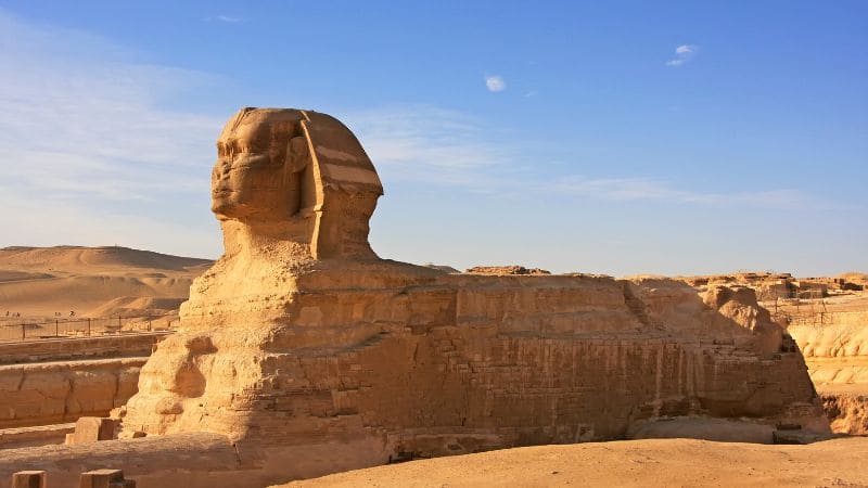 The Sphinx of Giza against a desert background with a clear blue sky.