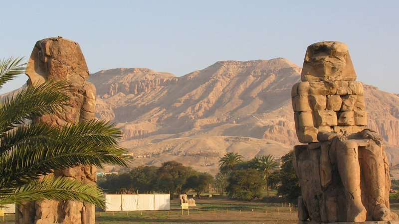 The towering statues of the Colossi of Memnon stand against the Theban mountains