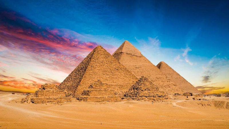 The Great Pyramids of Giza during sunset with a vibrant sky.
