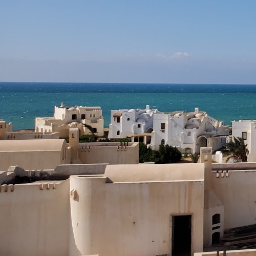 White coastal buildings overlooking a turquoise sea under a clear blue sky