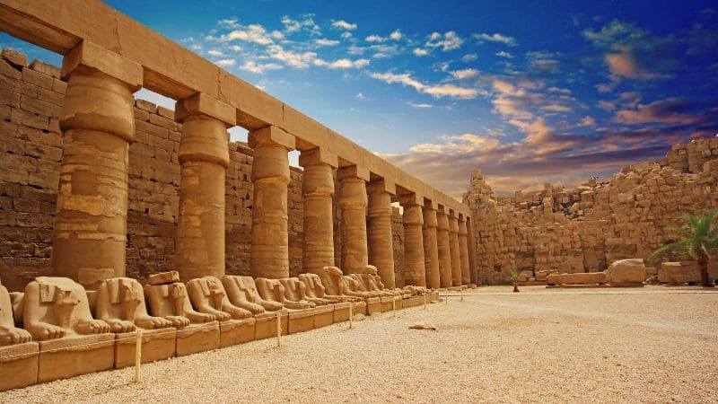 Row of sphinx statues at the entrance to an ancient temple.