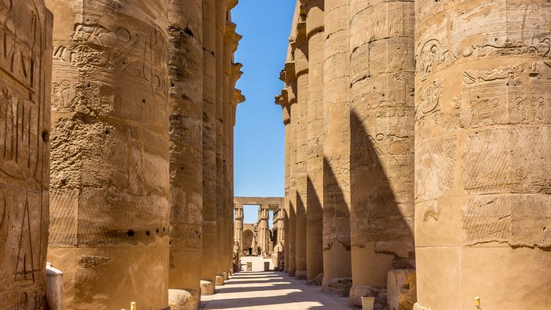 Sunlit corridor of pillars in Karnak Temple.