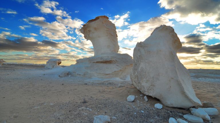 Dramatic chalk formations in the White Desert under a cloudy sky.