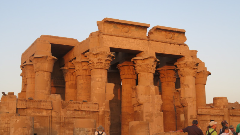 A warm sunset illuminates the columns and ruins of an Egyptian temple